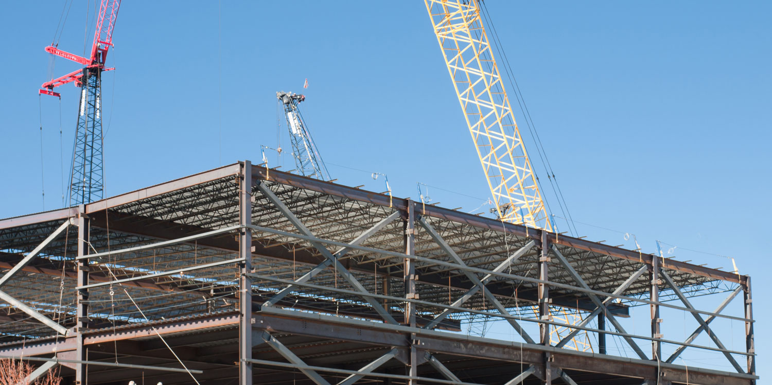 Crane lifting materials at steel frame construction site.
